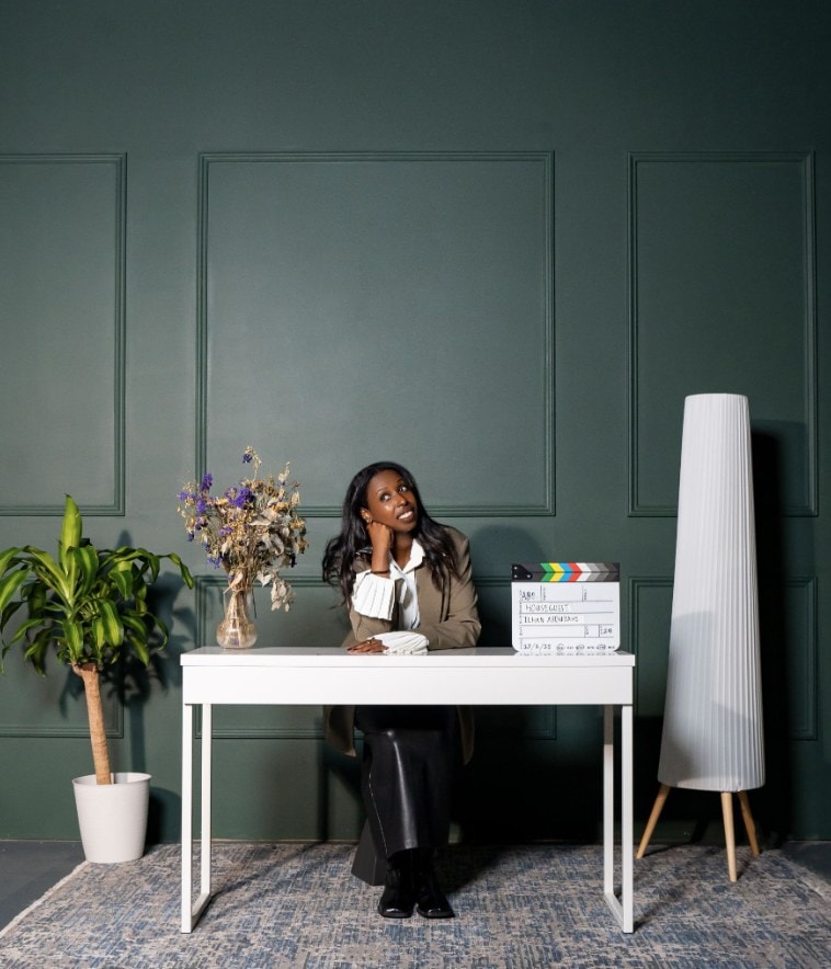 Ilhan Abdullahi at a desk with a clapperboard for her film The Houseguest
